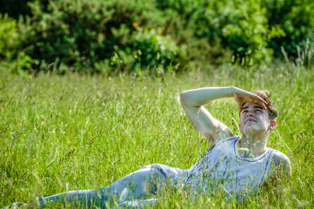A young adult male laying amoung long grass on a warm summer's dayの写真素材