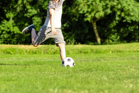 Pre-teen boy playing with a football in a parkの写真素材