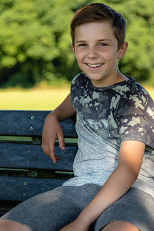 Pre-teen boy sitting outside on a warm summer's dayの写真素材