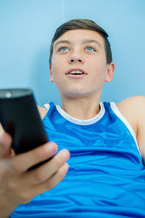 Caucasian teenage boy flicking through tv channels with a remote control