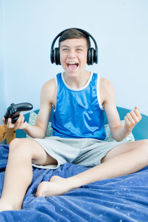 Teenage boy playing a video game while on his bed