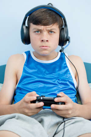 Teenage boy playing a video game while on his bed, losingの写真素材