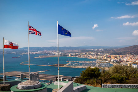 Gibraltar, United Kingdom, 1st October 2018:- View from the top of the Rock of Gibraltar looking North into Spain, with the flags of Gibraltar, UK and EU flying. Gibraltar is a British Overseas Territory located on the southern tip of Spain.のeditorial素材