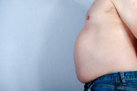 Overweight shirtless caucasian man standing up viewed from the side