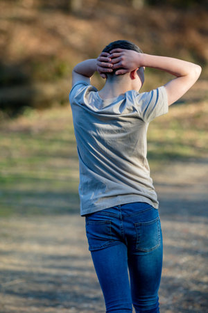 Caucasian teenage boy dancing with his back to the camera on a warm spring day