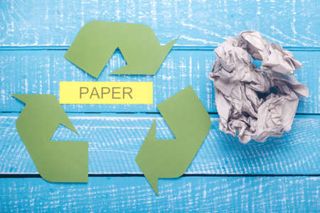 Recycle concept showing paper with the green recycle logo on a blue weathered backgroundの写真素材
