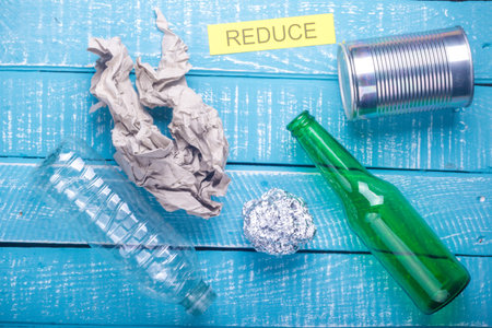 Recycle concept showing waste products of paper, glass, plastic, foil paper & reduce on a blue...