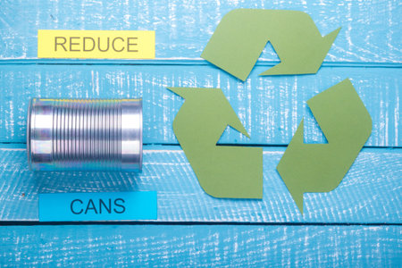 Recycle concept showing green recylce logo with cans on a blue weathered background and reduce