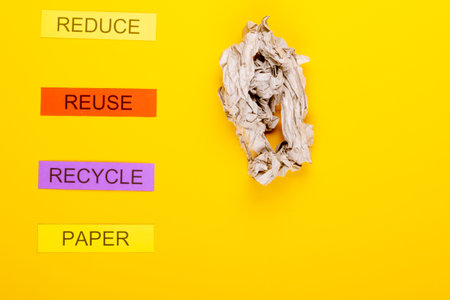 Recycling concept showing reduce, reuse, recycle & paper on a yellow backgroundの写真素材