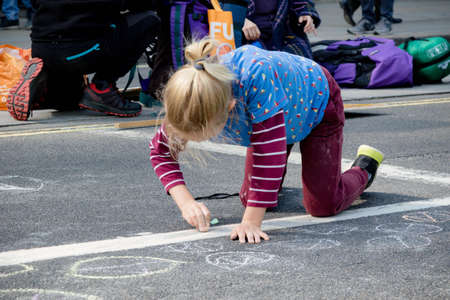 London, United Kingdom, 15th April 2019:- Extinction Rebellion child protester draws on the road outside Parliament when protesting climate changeのeditorial素材