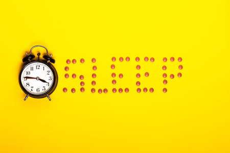 Sleep concept showing sleeping pills and an alarm clock on a yellow background
