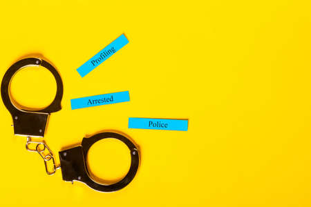 Crime concept showing handcuffs on a yellow background with Profiling Arrested Policeの写真素材