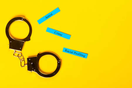 Crime concept showing handcuffs on a yellow background with Racial Profilingの写真素材