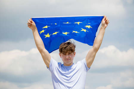 Young adult caucasian male holding on a beach holding the flag of the European Unionの写真素材