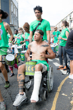 London, United Kingdom, August 25th 2019:-A shirtless samba drummer in a wheel chair at the Notting...