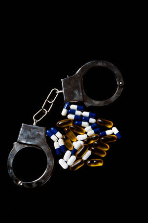 Illegal drug crisis concept showing pills and handcuffsの写真素材
