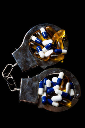 Illegal drug crisis concept showing pills and handcuffsの写真素材