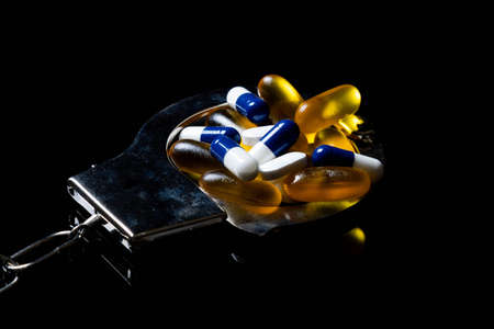 Illegal drug crisis concept showing pills and handcuffsの写真素材