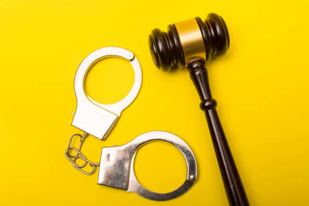 Crime or justice concept showing a gavel on a yellow background with handcuffsの写真素材