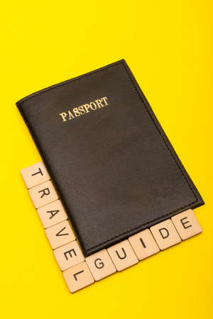 Travel concept showing a passport with a sign reading travel guide on a yellow backgroundの写真素材