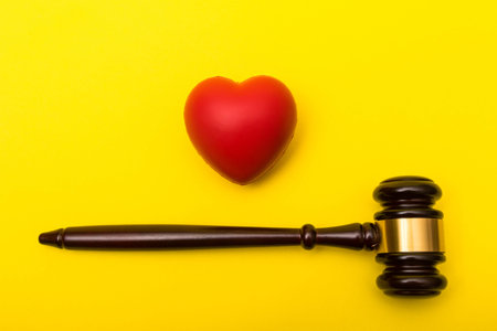 Medical malpractice lawsuit concept showing a gavel and a heart on a yellow background