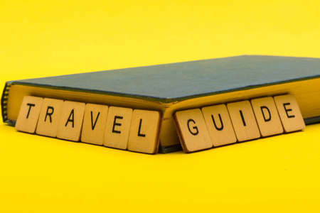 Travel concept showing a book with a sign reading travel guide on a yellow backgroundの写真素材