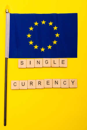 European union concept showing the flag of the EU on a yellow background with a sign reading single currencyの写真素材