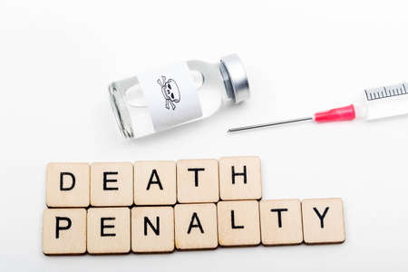 A glass medical vial with a skull and crossbones on a white background with a sign reading Death Penalty and a Syringeの写真素材