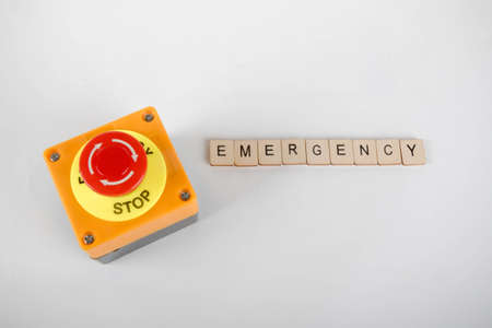 An industrial emergency stop button with a sign reading Emergencyの写真素材