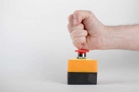 An industrial emergency stop button with a fist pressing downの写真素材