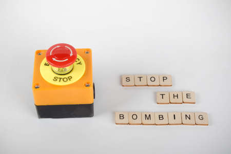 An industrial emergency stop button with a sign reading Stop The Bombingの写真素材