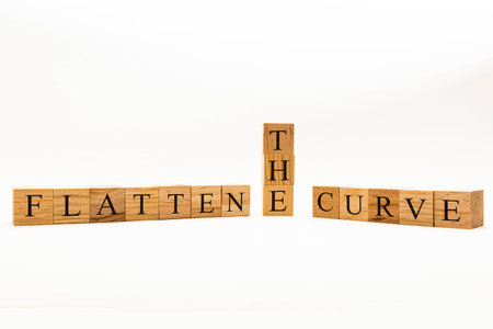 Coronavirus concept showing wooden blocks on a white background reading Flatten The Curve
