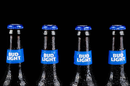 Sandhurst, United Kingdom; February 13th 2021:- The necks of four chilled bottles of Bud Light, isolated on a black backgroundのeditorial素材
