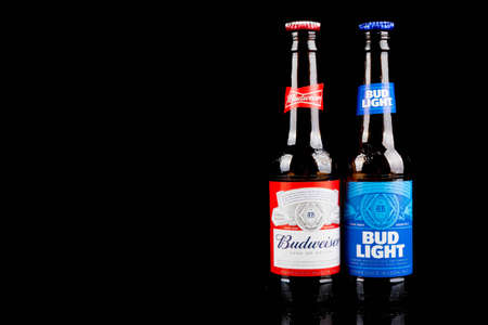 Sandhurst, United Kingdom; February 16th 2021:- Two open bottles of Bud Light & Budweiser  with lids on the lip, isolated on a black backgroundのeditorial素材