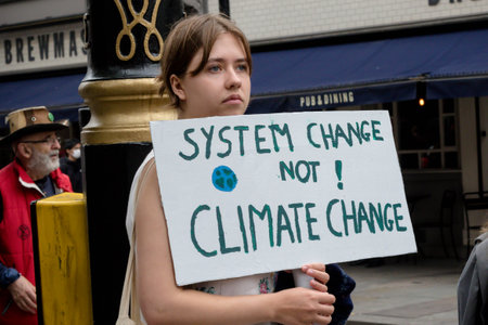 London, United Kingdom, 21st August 2021:- Extinction Rebellion protester holding a sign reading System Change Not Climate Changeのeditorial素材