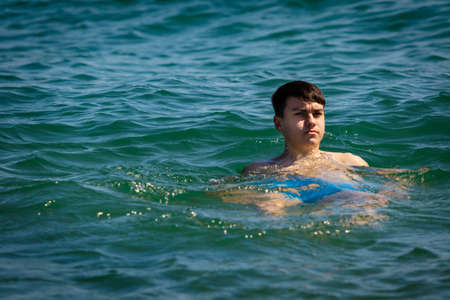 A 18 year old Caucasian shirtless teenage boy in swimwear relaxing in the seaの写真素材