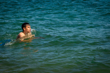 A 18 year old Caucasian shirtless teenage boy in swimwear swimming  in the seaの写真素材