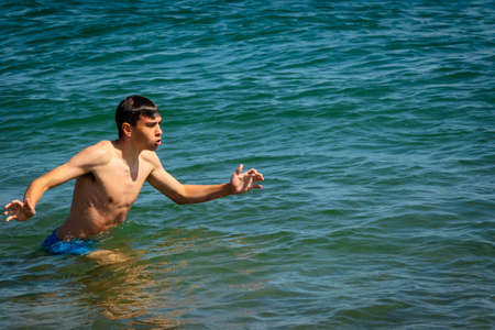 A 18 year old Caucasian shirtless teenage boy in swimwear diving in the seaの写真素材