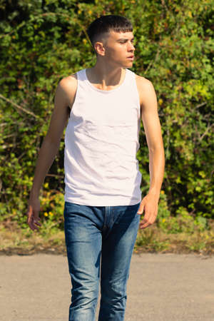 An 18 year old teen boy in a sleeveless top on a late summer's dayの写真素材