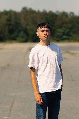 18 year old teen boy in a white t-shirt outdoors and blue denim jeans