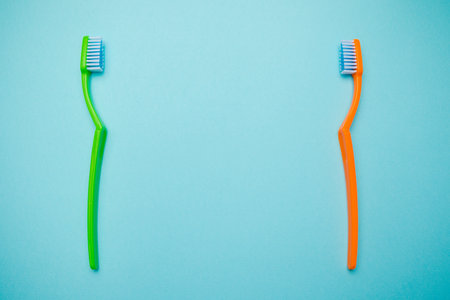 Oral and dental health concept showing two toothbrushes on a blue coloured background