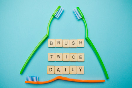Oral and dental health concept showing three toothbrushes with a sign reading brush twice daily on a...