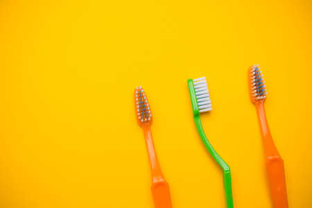 Oral and dental health concept showing three toothbrushes on a yellow coloured backgroundの写真素材