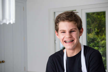 A portrain of a smiling teenage boy in a domestic kitchenの写真素材