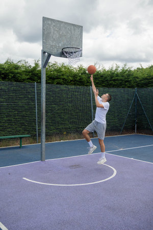 A Nineteen Year Old Teenage Boy Shooting A Hoop in A Basketball Court in A Public Park