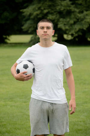 A Nineteen Year Old Teenage Boy Playing Football in A Public Parkの写真素材