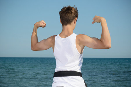 A 17 Year Old Teenage Black Belt Flexing His Muscles on A Beach