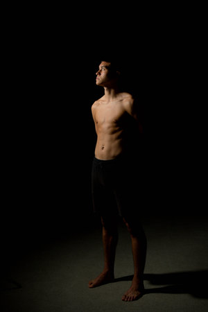 19 year old teen boy's body side view on a black backgroundの写真素材
