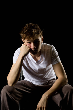 Portrait of a sitting emotional looking 17 year old teenage boy