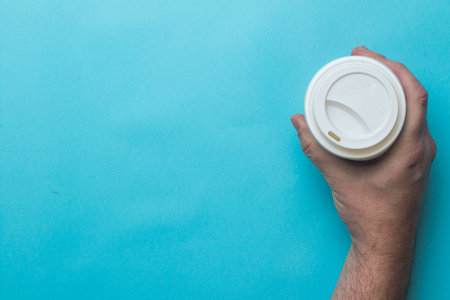 A paper coffee cup and lid held by a human handの写真素材